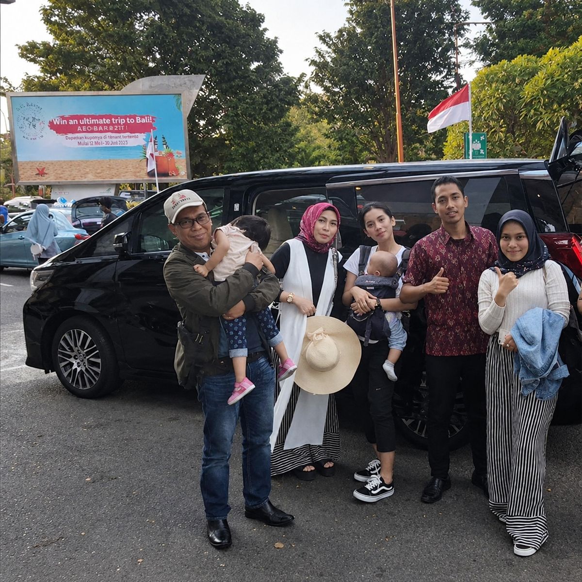 Keluarga pelanggan berfoto di depan mobil sewaan